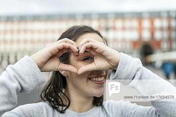 Happy young woman gesturing heart sign