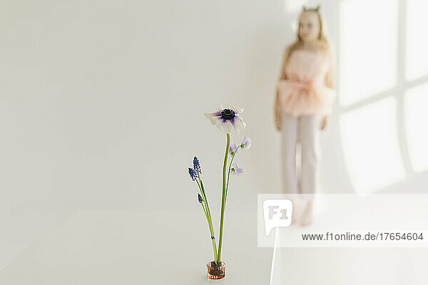 Fresh flower with girl standing behind in front of white wall