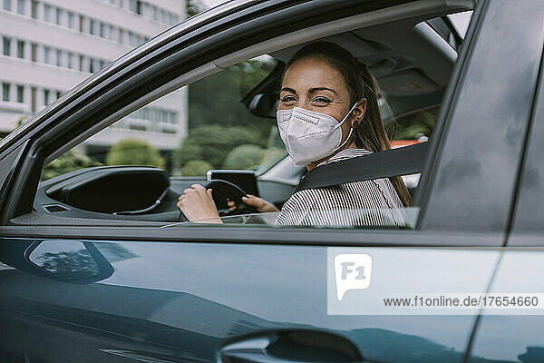 Young woman wearing protective face mask looking through car window