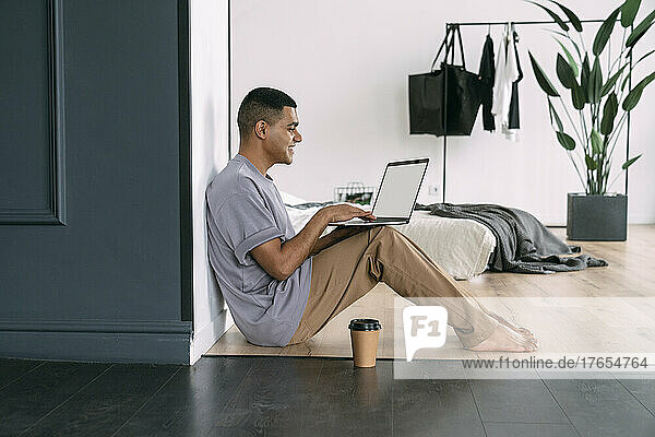 Smiling man using laptop sitting at home