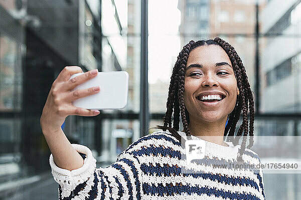Glückliche junge Geschäftsfrau  die im Büropark ein Selfie mit dem Mobiltelefon macht
