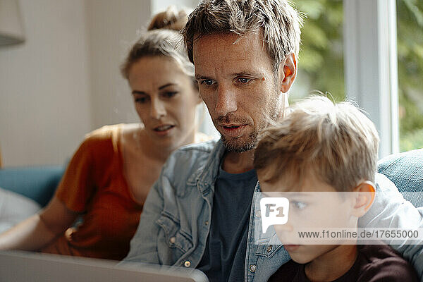 Family sharing laptop together at home