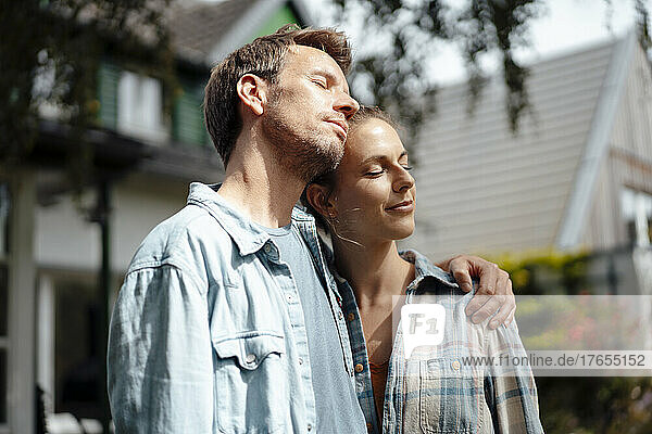 Paar mit geschlossenen Augen genießt den sonnigen Tag im Hinterhof