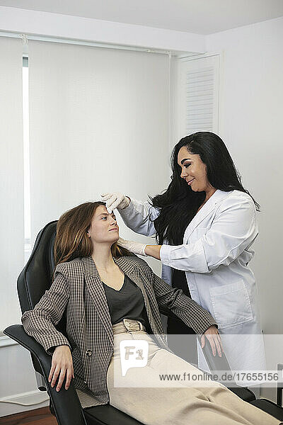 Dermatologist examining patient at aesthetic clinic