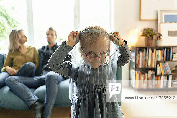 Cute little girl wearing eyeglasses playing in living room at home