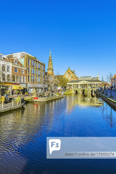 Netherlands  South Holland  Leiden  Clear blue sky reflecting in city canal with arch bridge in background