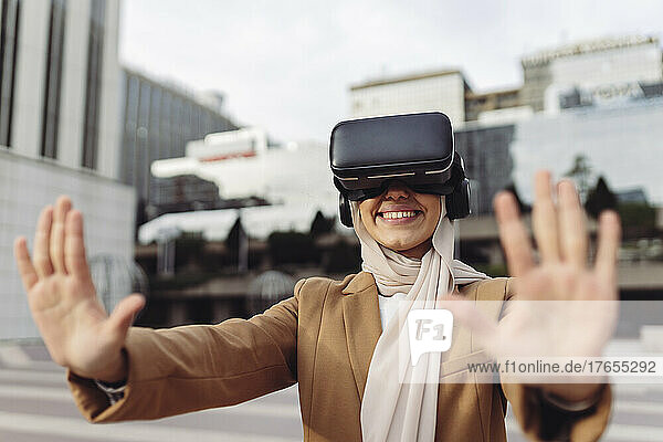 Happy businesswoman wearing virtual reality simulator gesturing stop sign