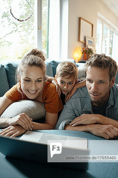 Smiling woman with man and son watching video on laptop at home