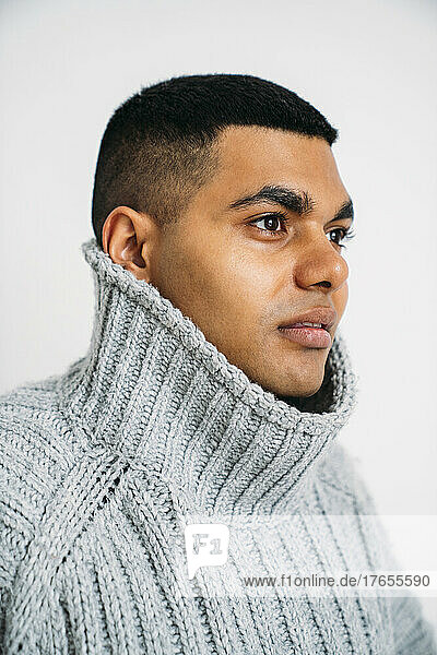 Young man wearing gray sweater against white background