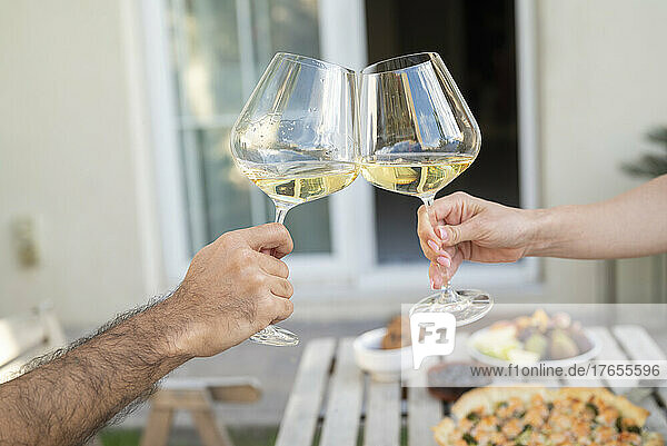 Hands of couple toasting with wineglasses in garden