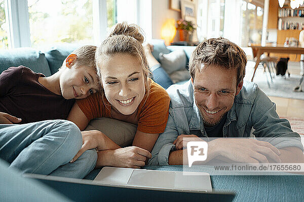 Smiling mother and father watching video with son through laptop in living room