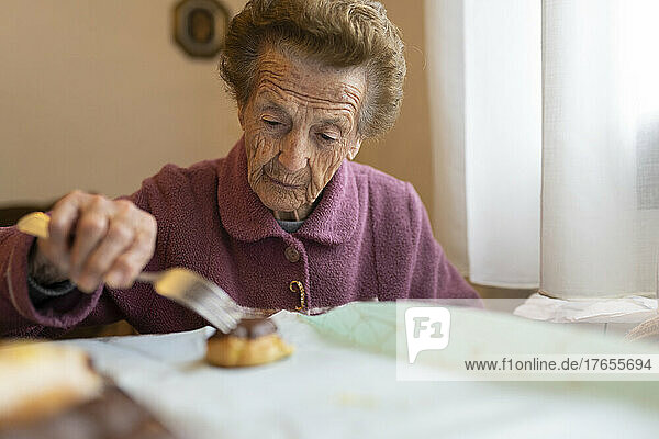 Senior woman with cupcake sitting at dining table