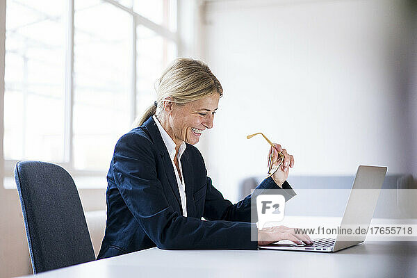Glückliche Geschäftsfrau  die Laptop am Schreibtisch im Büro benutzt