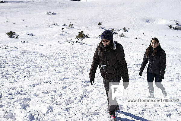 Two women hiking on snow covered mountain