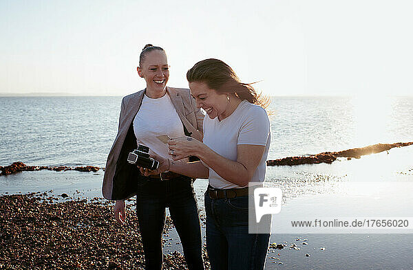 lesbian couple laughing at the beach taking selfies