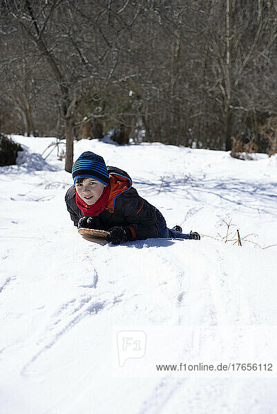 Boy slides down from the snow slope.
