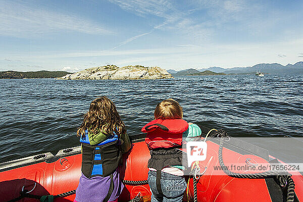 Two young kids look over the bow of a rubber raft in big bay