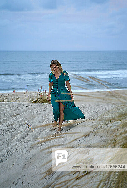 elegant woman walks along the beach pensive