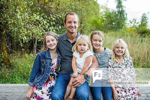 Portrait of father sitting with his four beautiful daughters.