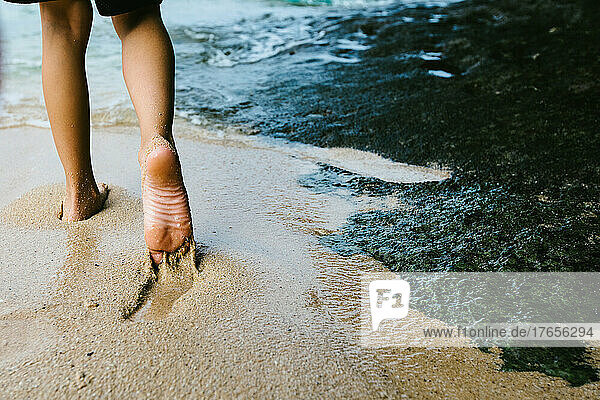 Boys feet in wet beach sand on the edge of the ocean