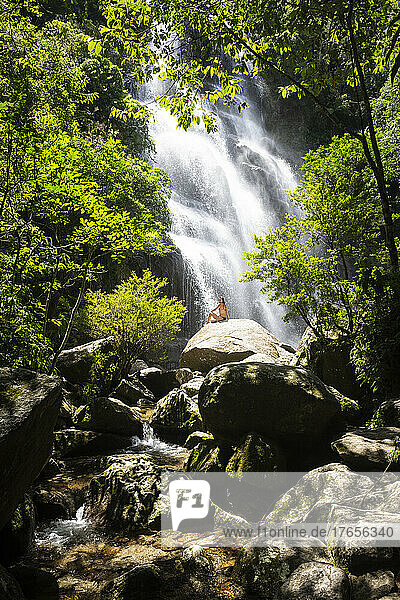 Beautiful view to woman enjoying green atlantic rainforest waterfall