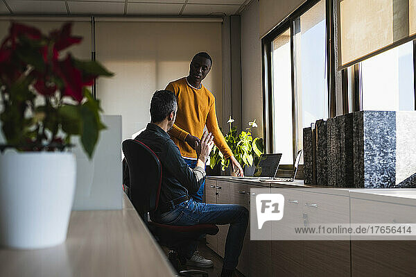 Two men of different ethnicities working in an office.