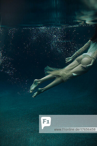 A young woman swims underwater on a gloomy day