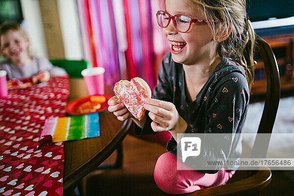Blond girl child with friend and heart cookie for Valentines