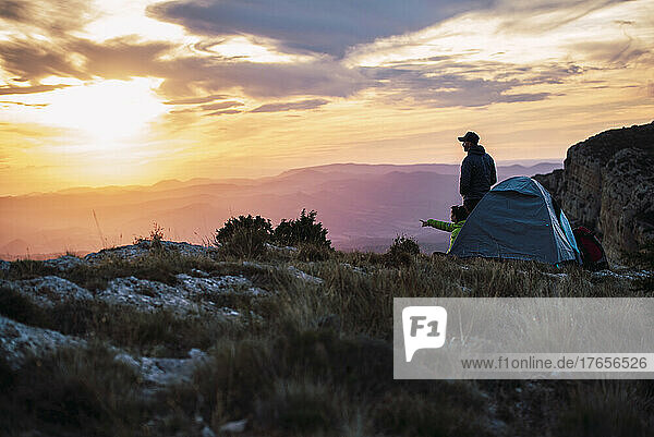 Couple camping in the mountains enjoying the sunset.