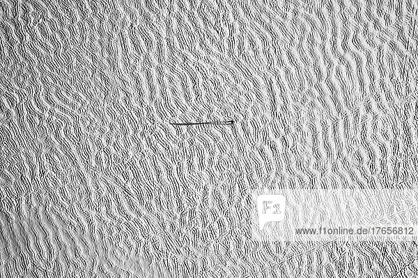 Aerial view of snow covered frozen lake with tiny figure and shadow