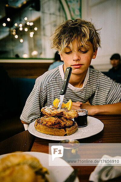 Teen Boy Looks at his Giant Breakfast of Fried Chicken and Waffles