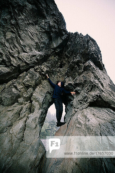 Hooded Teen Climbs Rock Cliff in Olympic National Park
