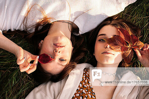 Overhead view of two teenage girls lying on grass during autumn