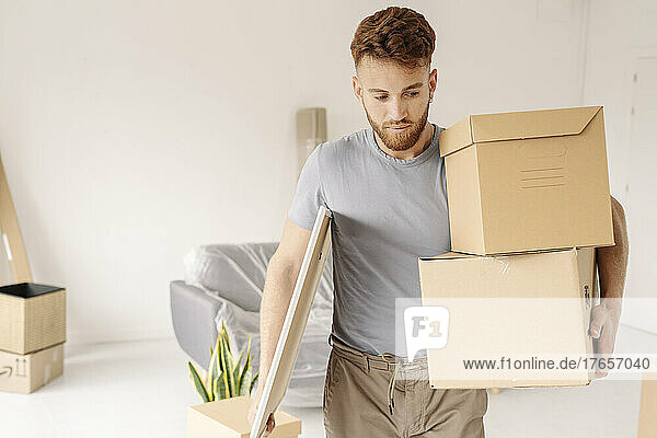 Thoughtful young man carrying cardboard box on his new house