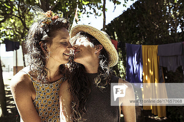 Two natural looking queer women kiss while camping