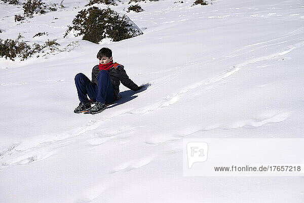 Boy slides down from the snow slope. Enjoying the winter sledding time