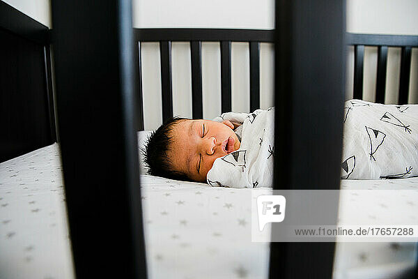Newborn baby sleeps soundly in his crib