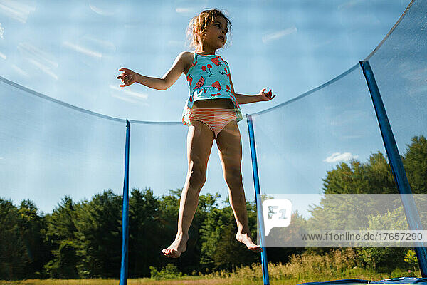 Young girl jumping on trampoline in air