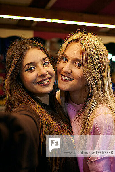 Two young women smiling and taking a selfie at night