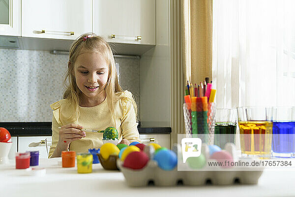 A smile girl paints Easter eggs.
