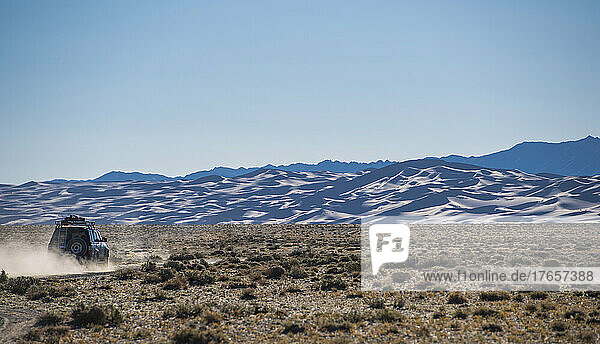 SUV driving past the great sand dunes of the Gobi desert