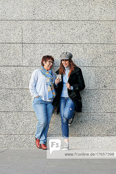 Mother and daughter with a phone and casual clothes in the street