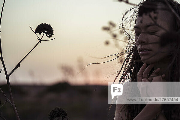 portrait of a dancer in the wind at dusk with coastal flowers