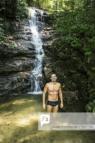 Beautiful view to man enjoying waterfall on green rainforest area