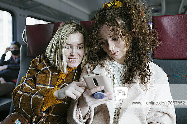 Two women on the train look at the phone
