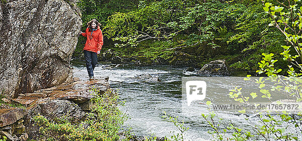 Woman walking along a stream at Snowdonia National Park