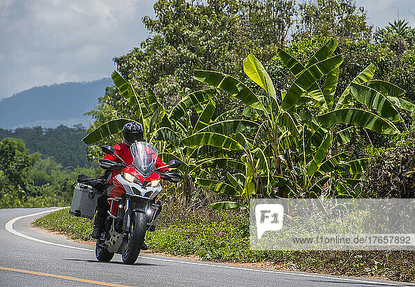 Man riding his adventure motorcycle on the roads of north Thailand