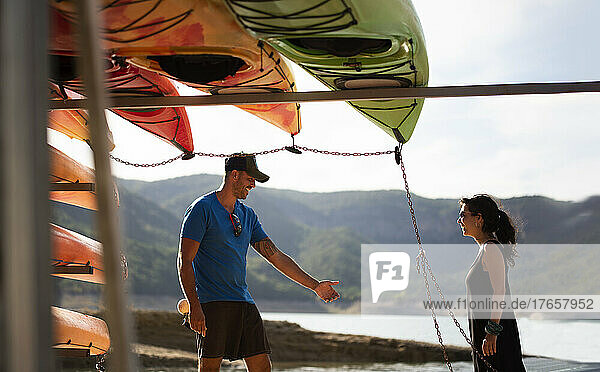 Young couple joking at a kayak landing on a mountain reservoir.