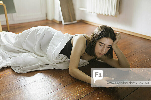 woman lying on wooden floor with phone