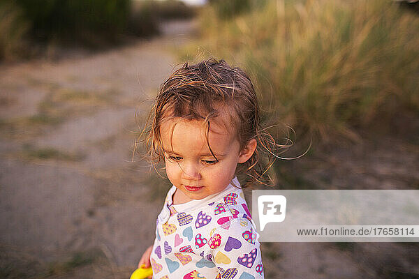 A young girl walks on beach at sunset in pajamas